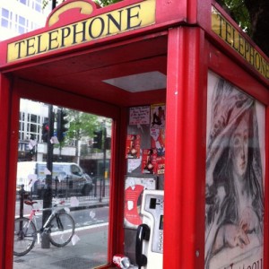 Telephone booth with official advertisment (outside) and unofficial ads and transactions (inside)